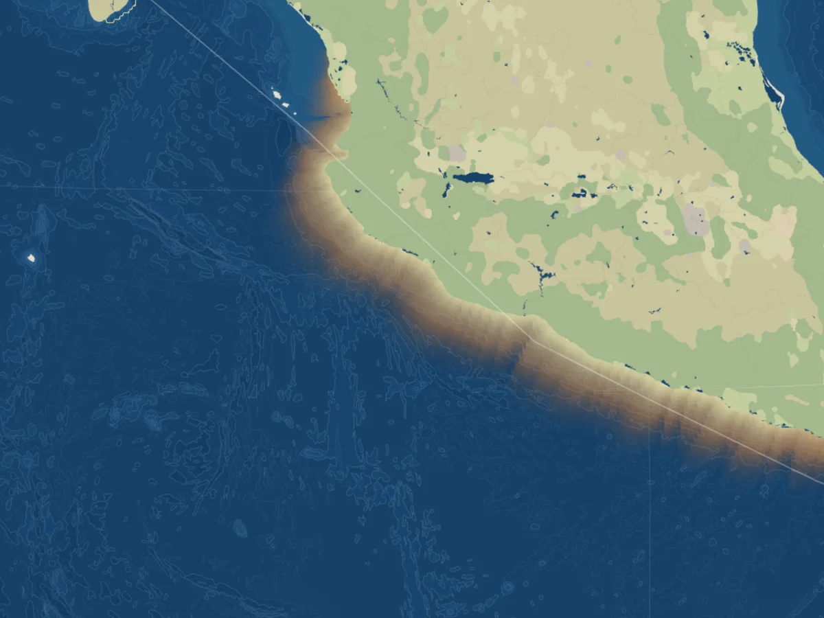 The Pacific coast of Mexico in late September: a narrow amber glow hugs the coastline and fades into the dark blue ocean within a short distance of the shore.